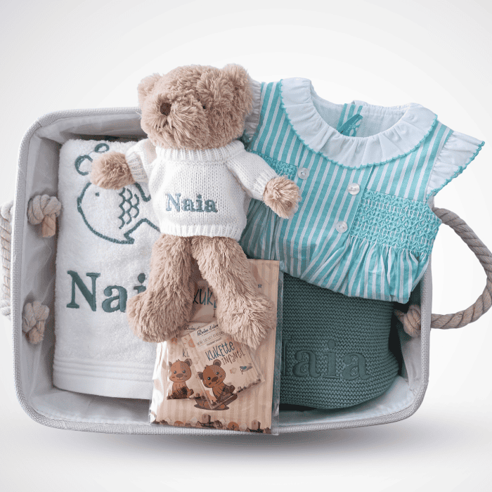 Ropa de verano para niña en canastilla con osito de peluche y accesorios.